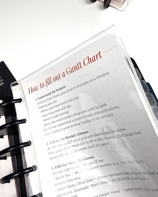 Gantt chart instruction sheet inside a discbound planner sleeve with a disc planner on a white background