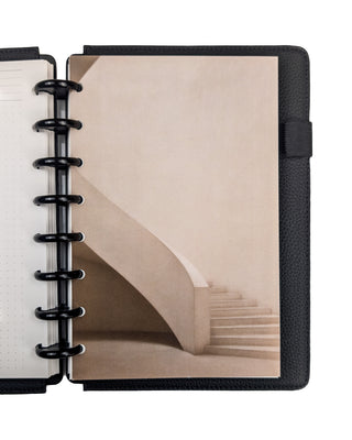 A minimalist beige spiral stairway disc bound planner dashboards, snapped into a planner with Black Plastic Discs and Black Vegan Leather Snap-on Cover on a white background. 