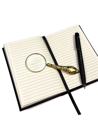Black Notebook wIth a pen and a magnifying glass.