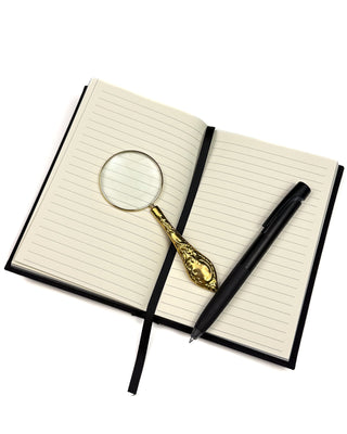 Lined Notebook with a pen and a golden magnifying glass.