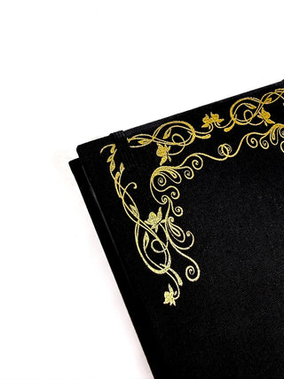 The corner of a black journal with gold highlights around the edges.