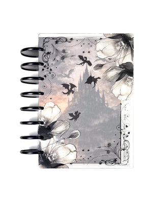 Discbound planner with black discs featuring clear floral planner covers layered over a moody castle dashboard with flying dragons, creating a gothic-inspired planner design.