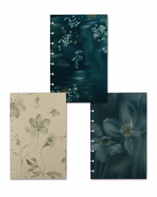 Three removable discbound planner dashboards displayed together, featuring coordinating watercolor botanical designs. The collection includes a cream dashboard with soft sage florals, a deep teal dashboard with scattered white blossoms, and a moody blue-green dashboard with oversized translucent white flowers.