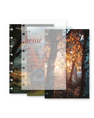 Three layered Jane’s Agenda discbound planner dashboards featuring cozy autumn scenery. The center translucent vellum dashboard displays the word “home” with a heartfelt definition about love and belonging, layered over a rustic cabin scene. The surrounding dashboards feature a peaceful lakeside landscape and golden fall foliage illuminated by warm sunlight.
