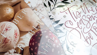 Decorative Christmas ornaments with 'Vibrant' branding and festive text on a patterned background.