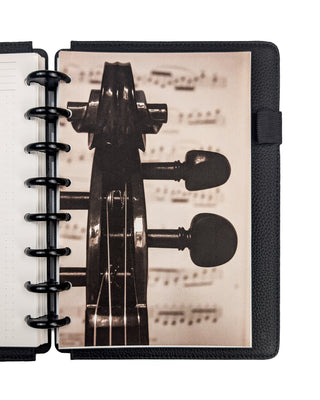 Sepia-toned heavy cardstock dashboard for discbound planners featuring a cello scroll with blurred sheet music in the background. Snapped into a planner with Black Plastic Discs and Black Vegan Leather Snap-on Cover on a white background. 