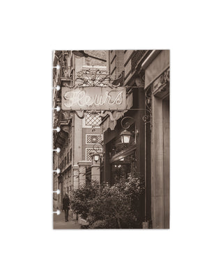 Heavy cardstock discbound planner dashboard showing a vintage French street with a glowing “Fleurs” sign, architectural details, and lush greenery in sepia tones on a white background. 