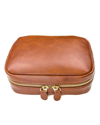 Front view of a warm brown leather zippered planner case displayed against a clean white background. The case features a smooth, lightly textured finish, rounded corners, gold-tone dual zipper hardware, and matching leather zipper pulls for a timeless, polished look.
