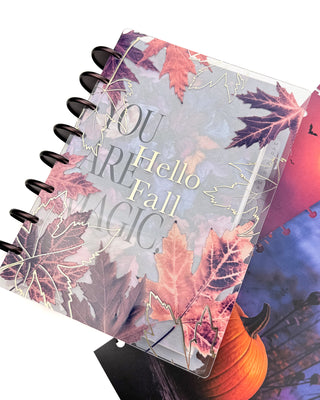Jane’s Agenda discbound planner with dark metallic discs, featuring a clear fall leaf cover layered over a “You Are Magic” dashboard and “Hello Fall” design, with a pumpkin-themed dashboard visible underneath.