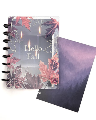 Open Jane’s Agenda discbound planner with dark metallic discs, featuring a clear “Hello Fall” cover decorated with pink and burgundy maple leaves layered over a glowing candle dashboard, alongside a coordinating misty purple forest dashboard.
