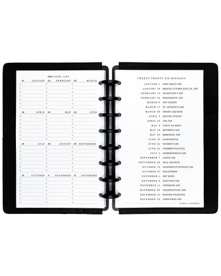 Black disc-bound planner with calendar pages on a white background