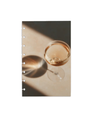 A glass of champagne disc bound planner dashboards on a white background.