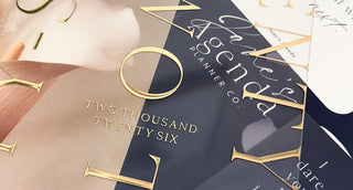 Discbound planner cover with gold and embossed text, featuring the year 2026 lying over other planner items.