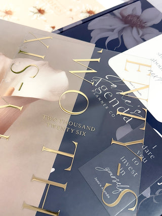 Discbound planner cover with gold and embossed text, featuring the year 2026 lying over other planner items.