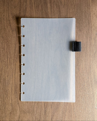 Frosted discbound planner dashboard with an elastic pen loop on a dark background. 