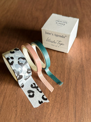 Set of washi tape with leopard print and solid colors next to a box labeled 'jane's Agenda' on a wooden surface.