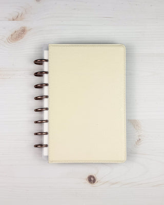 Beige discbound planner with metal binding discs on a light wooden surface