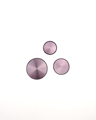 Three lavendar color metallic circular binding discs on a white background