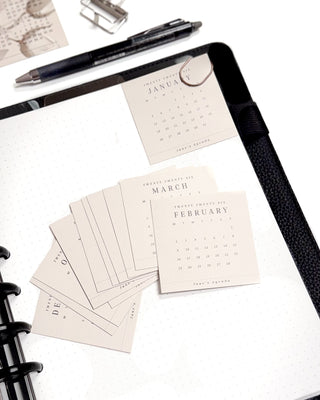 Calendar cards on a planner with a pen and paper clips.
