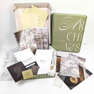 Collection of stationery items including notebooks, cards, and a box labeled 'Archives' on a light background.