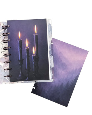 Open Jane’s Agenda discbound planner with dark metallic discs and monthly side tabs, featuring a dashboard with four glowing candles against a deep purple background, alongside a coordinating misty purple evergreen forest dashboard.