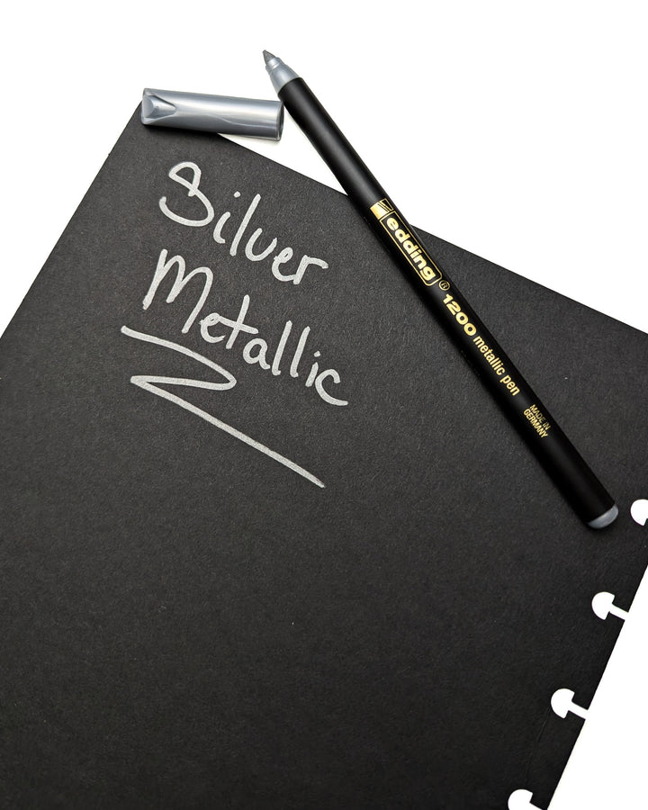 Edding metallic silver pen demonstrating vibrant metallic ink on dark black paper.