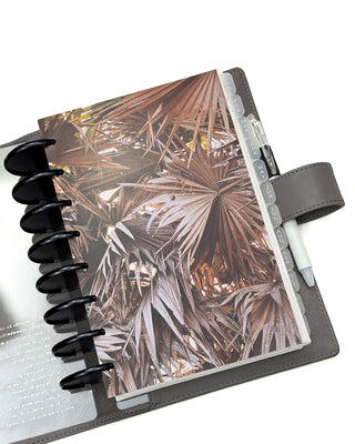 Planner with palm leaf design dashboard with pen holder, and white pen on a white background