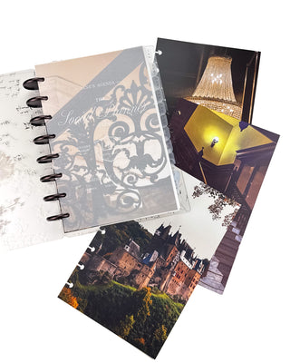 Open Jane’s Agenda discbound planner with dark metallic discs and monthly tabs, featuring a frosted “The Social Planner Club” dashboard layered over an ornate architectural design, with coordinating chandelier, staircase, and castle dashboards displayed beside it.