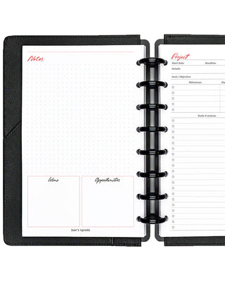 Project planner inserts inside a black discbound planner notebook over a white background.