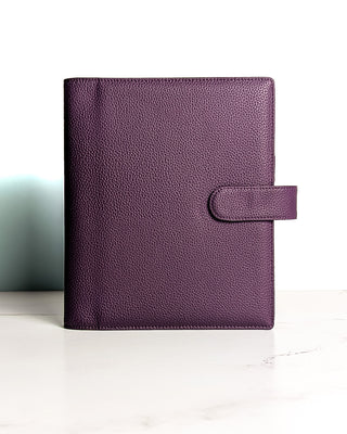 A closed purple leather planner wrap cover from Jane's Agenda with a textured finish and strap tab