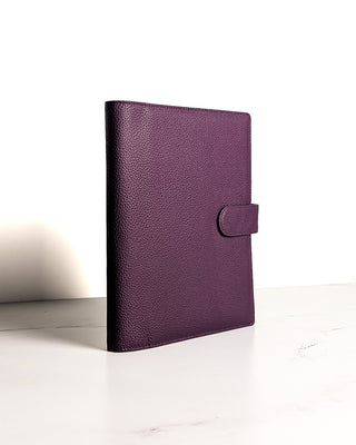 A closed purple leather planner wrap cover from Jane's Agenda with a textured finish and strap tab