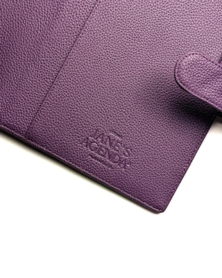 Close-up of the Jane’s Agenda logo embossed on the interior of a purple vegan leather planner cover near the strap closure.