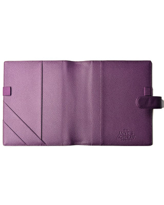 Flat lay of the full open interior of the purple leather planner wrap cover showing pockets, pen loops, and strap closure.