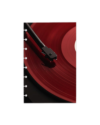 Close-up of a turntable needle on a red vinyl record with a white background