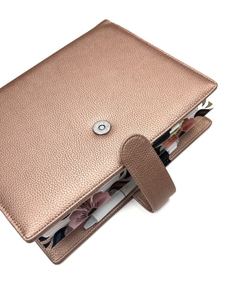 Rose gold vegan leather planner cover for discbound panners over a white background.