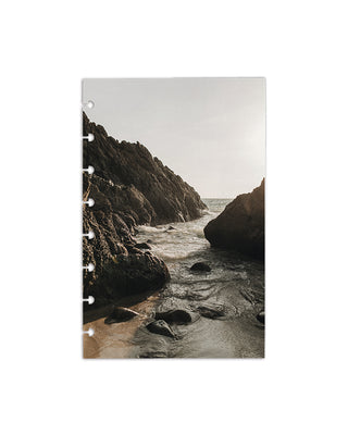 Featuring a rocky shoreline with ocean water flowing between coastal rocks, photographed in natural light on a white background