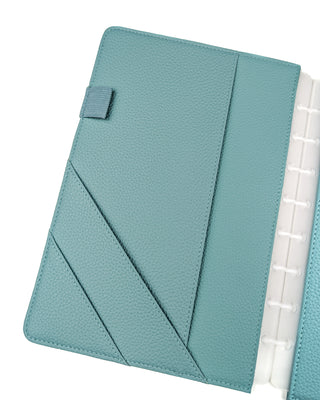 Light teal leather discbound planner cover front inside with three pockets and a pen loop over a wjite background.
