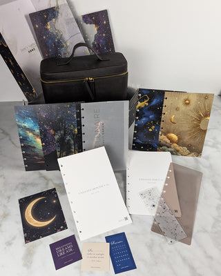 Collection of stationery items including notebooks and cards with celestial designs on a marble surface.
