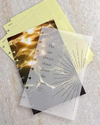 Layered Jane’s Agenda discbound planner dashboards and notes pages in soft yellow and gold tones, featuring a frosted dashboard with a sunburst design and the quote, “The sun always shines above the clouds.”