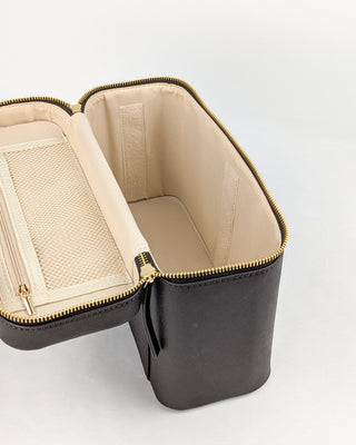 Inside view of a chocolate vegan leather train case with a gold metal zipper,  tan polyester fabric, and a mesh zipper pouch.