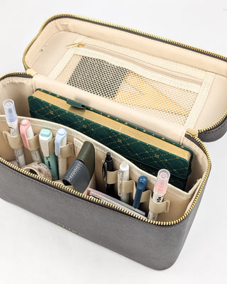 A chocolate brown vegan leather train case with pens and other accessories added.