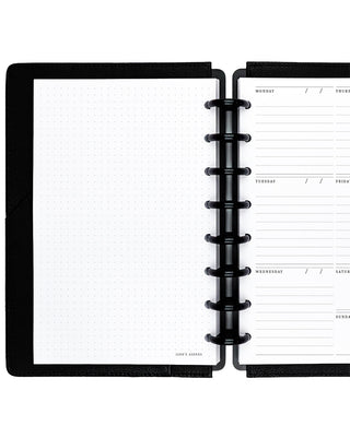 Open discbound planner with black binding discs on a white background