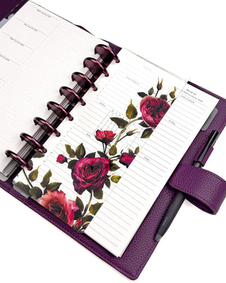 Featuring victorian-inspired vibrant rose glass clear plastic hybrid dashboard snapped onto a disc-bound planner. With Violet purple binding discs with a purple vegan leather wrap around cover on a white background. 
