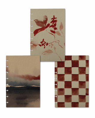 Three removable discbound planner dashboards displayed together, featuring a coordinated warm watercolor collection. Designs include an abstract botanical print in rich crimson and blush tones, a soft landscape in charcoal, taupe, and rust hues, and a hand-painted terracotta checkerboard pattern on a creamy beige background.