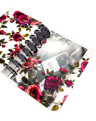 Discbound planner featuring the Vibrant Roses clear planner cover and the Romantic Locks dashboard layed underneath on a white background. 