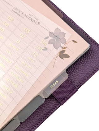 Purple planner with floral design and tab labeled 'Ideas' with other raised gold foiled adhesive labels on a white background