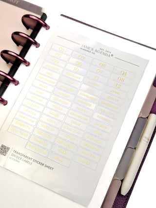 Transparent gold foiled divider labels over a discbound planner on a white background