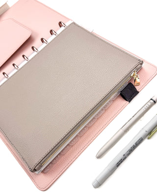 A Classic-size taupe brown vegan leather discbound zipper pouch displayed inside a blush pink vegan leather snap-on cover, classic size, with rose gold discs on a white background; with a Waai Pilot FiXion pen and a Sage Green Mildliner Highlighter. 