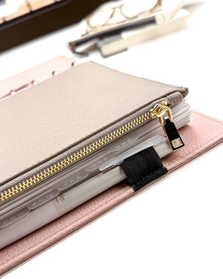 Close up of the gold metal zipper and pull, on the taupe brown zipper pouch on a classic size discbound planner. 