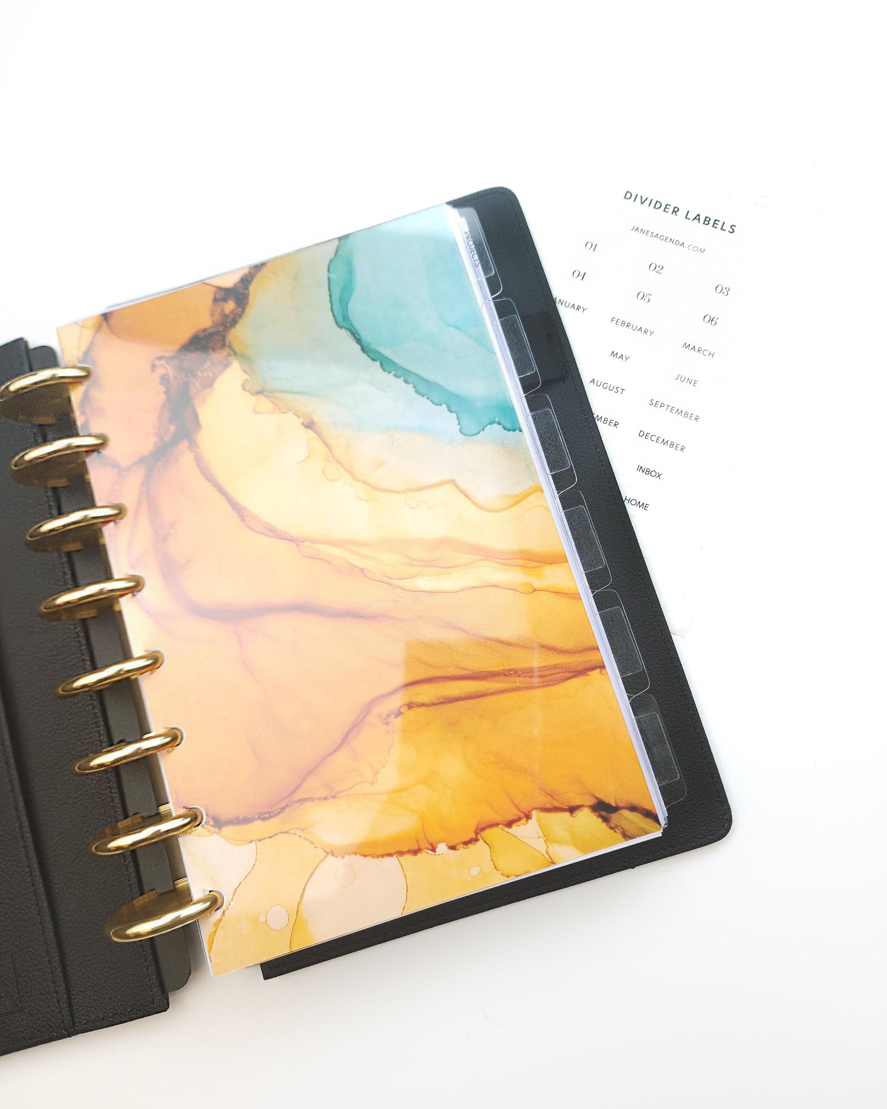 Clear plastic planner dividers that include clear adhesive divider labels to accomadate discbound and six ring planner systems by Jane's Agenda.